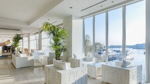 A spacious, modern lounge area with white, textured seating and large windows offering a view of a snowy landscape. - Hotel Marinoa Resort Fukuoka (Fukuoka)