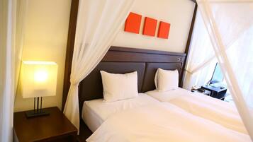 A hotel room with a bed, a nightstand, a lamp, and a window with curtains.