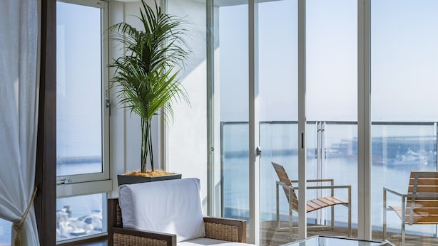 A modern balcony with a glass table, wicker chairs, and a potted plant. - Hotel Marinoa Resort Fukuoka (Fukuoka)