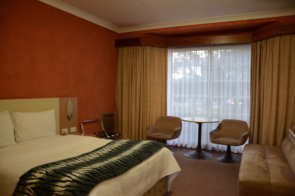 A hotel room with a bed, two armchairs, a small table, and a sofa.