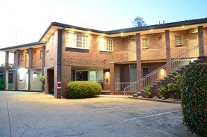 A two-story brick building with a covered front porch, a staircase, and a parking lot. - Motel Margeurita (Queanbeyan)