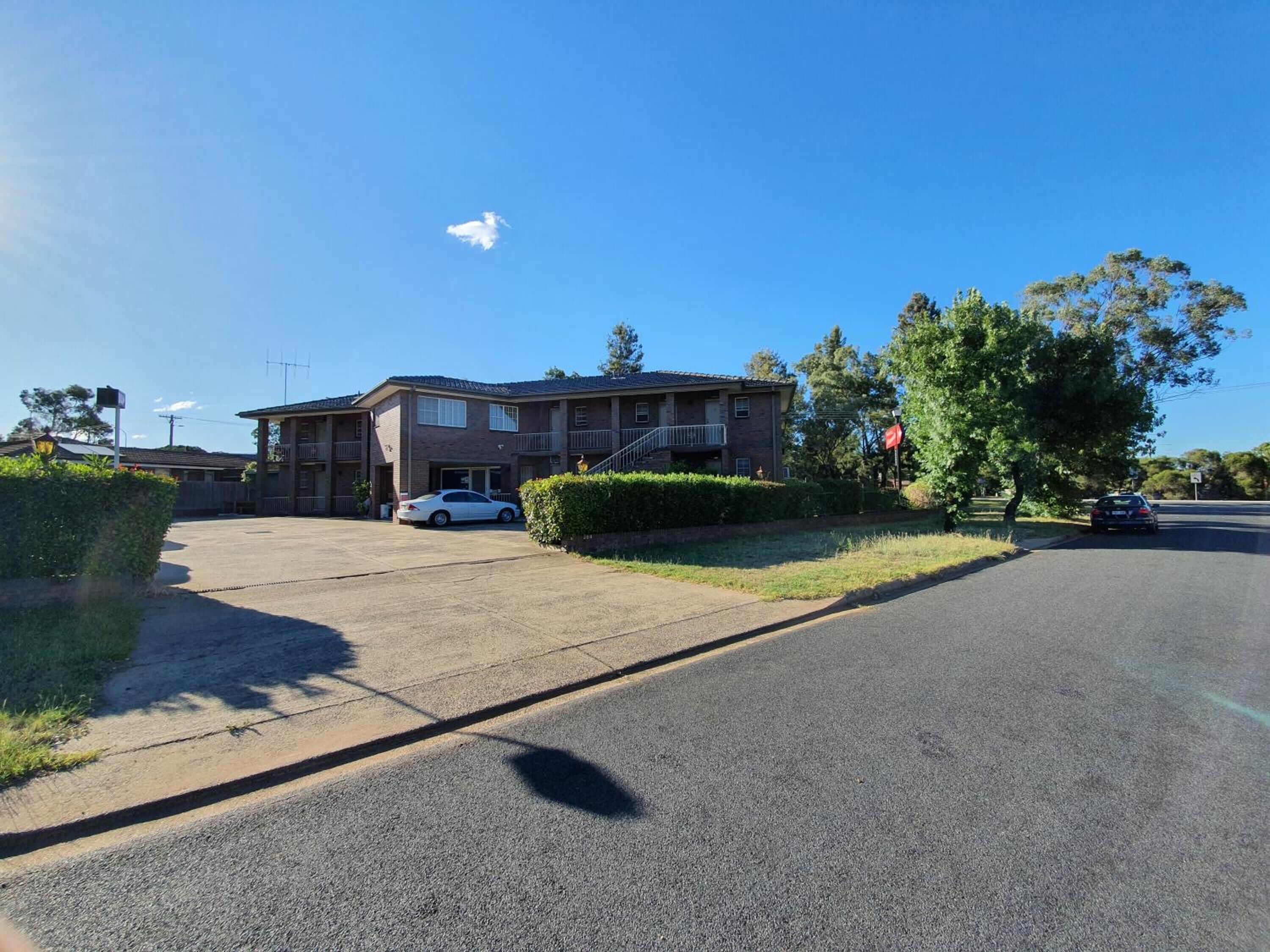 A two-story motel with a parking lot and a road in front.