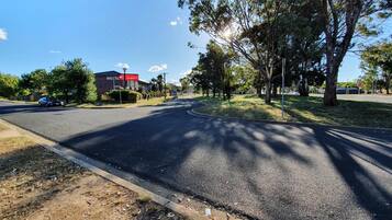 A road leading to a motel with a red sign, surrounded by trees and a clear sky.