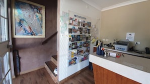 A reception area with a desk, a map display, and a staircase. - Motel Margeurita (Queanbeyan)