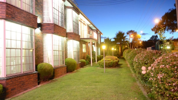 A multi-story building with large windows and a well-maintained lawn. - Motel Margeurita (Queanbeyan)
