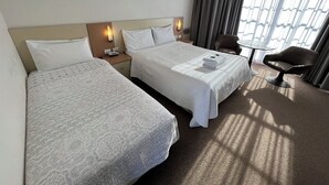 A hotel room with two beds, a desk, a chair, and a window with curtains. - Motel Margeurita (Queanbeyan)