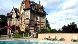 A pool area with lounge chairs and a red canopy. - Château de la Rapée (Bazincourt-sur-Epte)