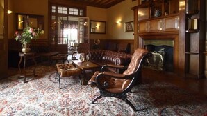 A traditional living room with a leather sofa, a patterned rug, and a fireplace. - Château de la Rapée (Bazincourt-sur-Epte)