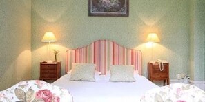 A bedroom with a striped headboard, two bedside lamps, a floral bedspread, and a framed picture on the wall.