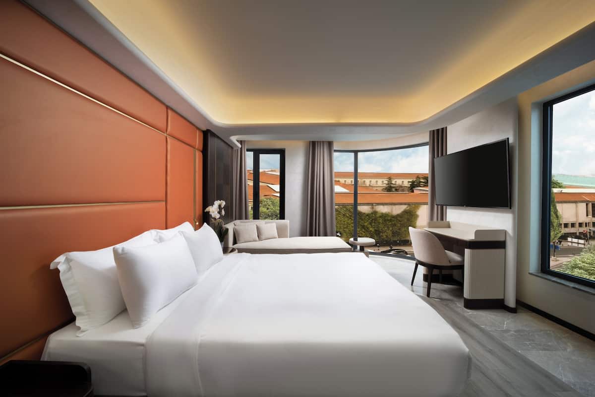 A hotel room with two beds, a desk, and a TV.