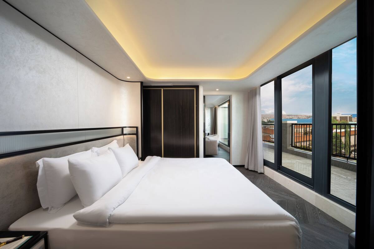A modern hotel room with a large bed, a view of the city, and a balcony.