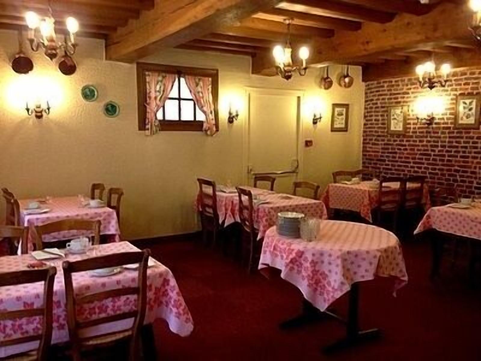 Un coin repas accueillant avec des tables et des chaises en bois, un mur en briques et des appliques murales décoratives.
