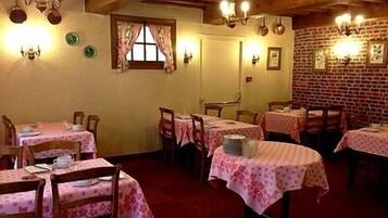 Un coin repas accueillant avec des tables et des chaises en bois, un mur en briques et des appliques murales décoratives.