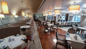 Een restaurant met verschillende eetgedeeltes, elk met tafels en stoelen, en grote hanglampen.