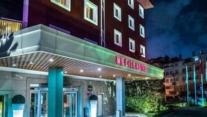 Een hotelentree met een modern ontwerp, inclusief een overdekt portaal en een bord waarop 