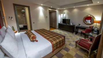 Una habitación de hotel con cama, escritorio, televisión, espejo y una silla.