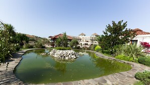A landscaped garden with a pond, stone pathway, and buildings in the background. - The Sign Şile Hotel & Spa (Sile)