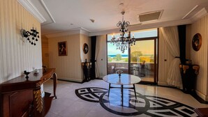 A spacious room with a large chandelier, a round table, and a view of the ocean through a sliding glass door. - The Sign Şile Hotel & Spa (Sile)