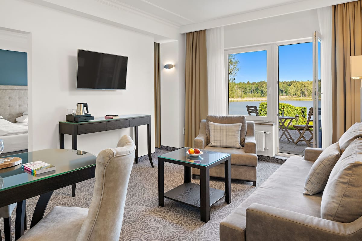Quarto de hotel com cama, escrivaninha, televisão, sofá e varanda com vista para o exterior.