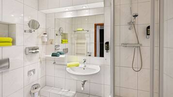 Un baño moderno con ducha de vidrio, lavamanos y espejo.