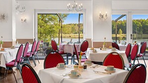 A dining area with tables set for service, chairs, and a view of a lake. - Seehotel Mühlenhaus (Chorin)