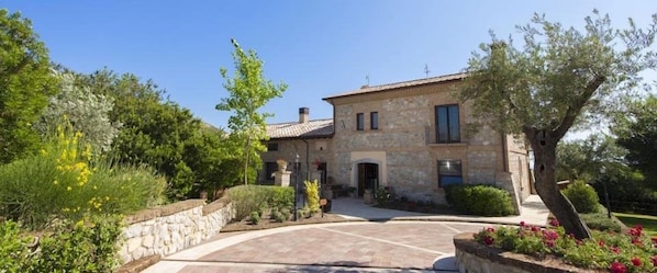 A stone building with a tiled roof, surrounded by greenery and a stone wall. - SarAnd Relais (Fondi)