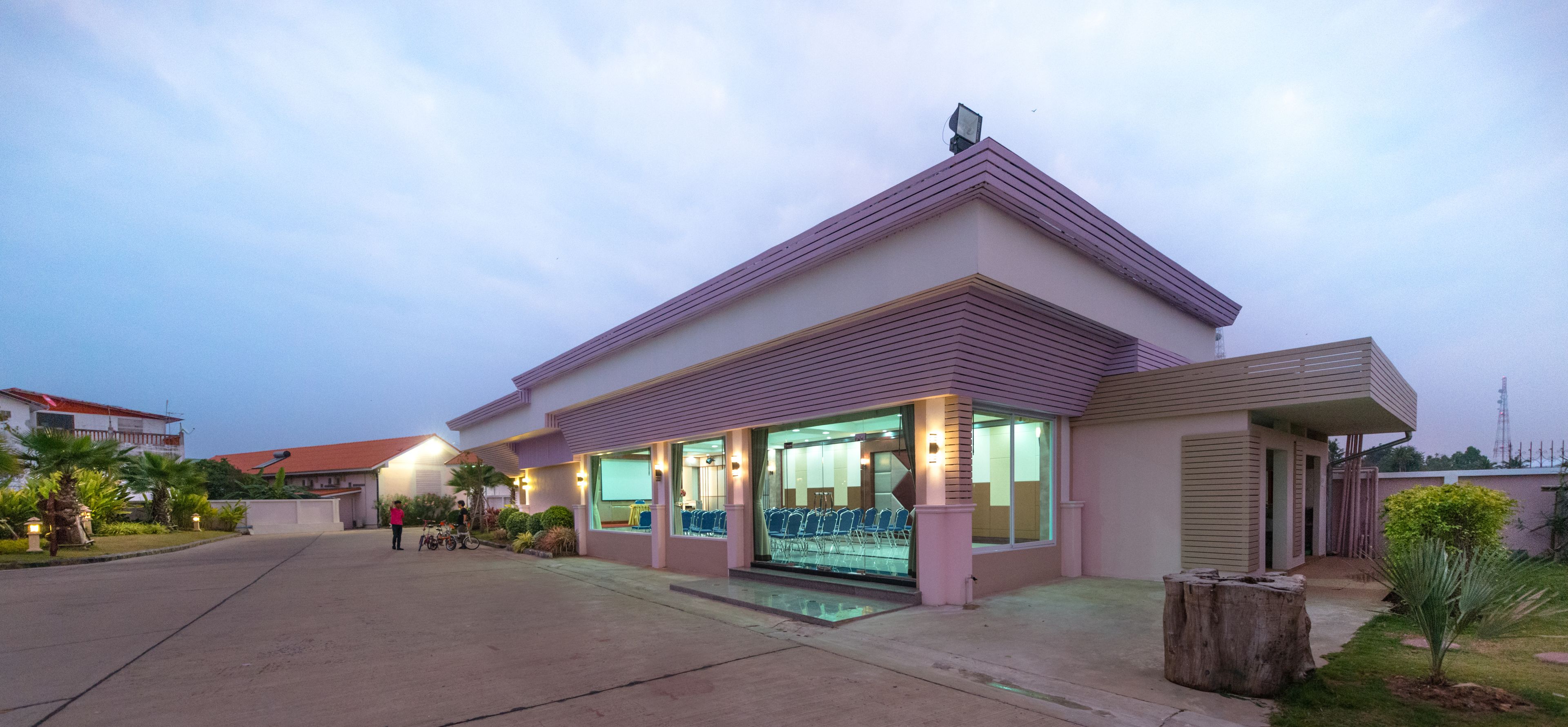 A modern building with a flat roof, large windows, and a covered outdoor seating area.