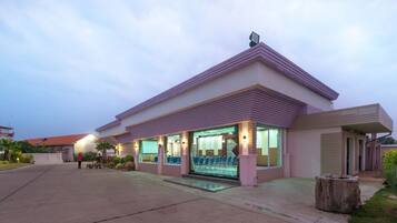 A modern building with a flat roof, large windows, and a covered outdoor seating area.