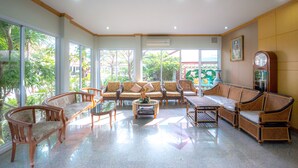 A spacious room with large windows, a sofa set, a coffee table, and a clock on the wall. - Martina Hotel (Surin)