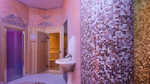 A bathroom with a mosaic wall, a pedestal sink, and wooden doors labeled "HAMMAM" and "SAUAN." - Gallery Room (Verona)