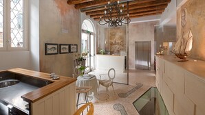 A kitchen with a wooden countertop, a sink, and a dining area with chairs and a table. - Gallery Room (Verona)