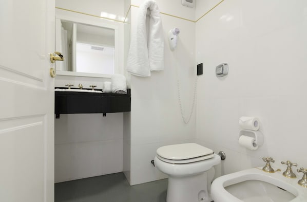 A modern bathroom with a toilet, bidet, and a sink with a towel rack. - Cyan Recoleta Hotel (Buenos Aires)