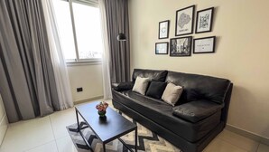 Una sala de estar moderna con un sofá de cuero negro, una mesita con un florero y una alfombra estampada.