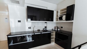 Una cocina moderna con armarios blancos y negros, un microondas y una tetera.