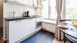 A modern kitchen with white cabinets, a stainless steel sink, and a window with curtains. - Plantage Hortus Apartments (Amsterdam)