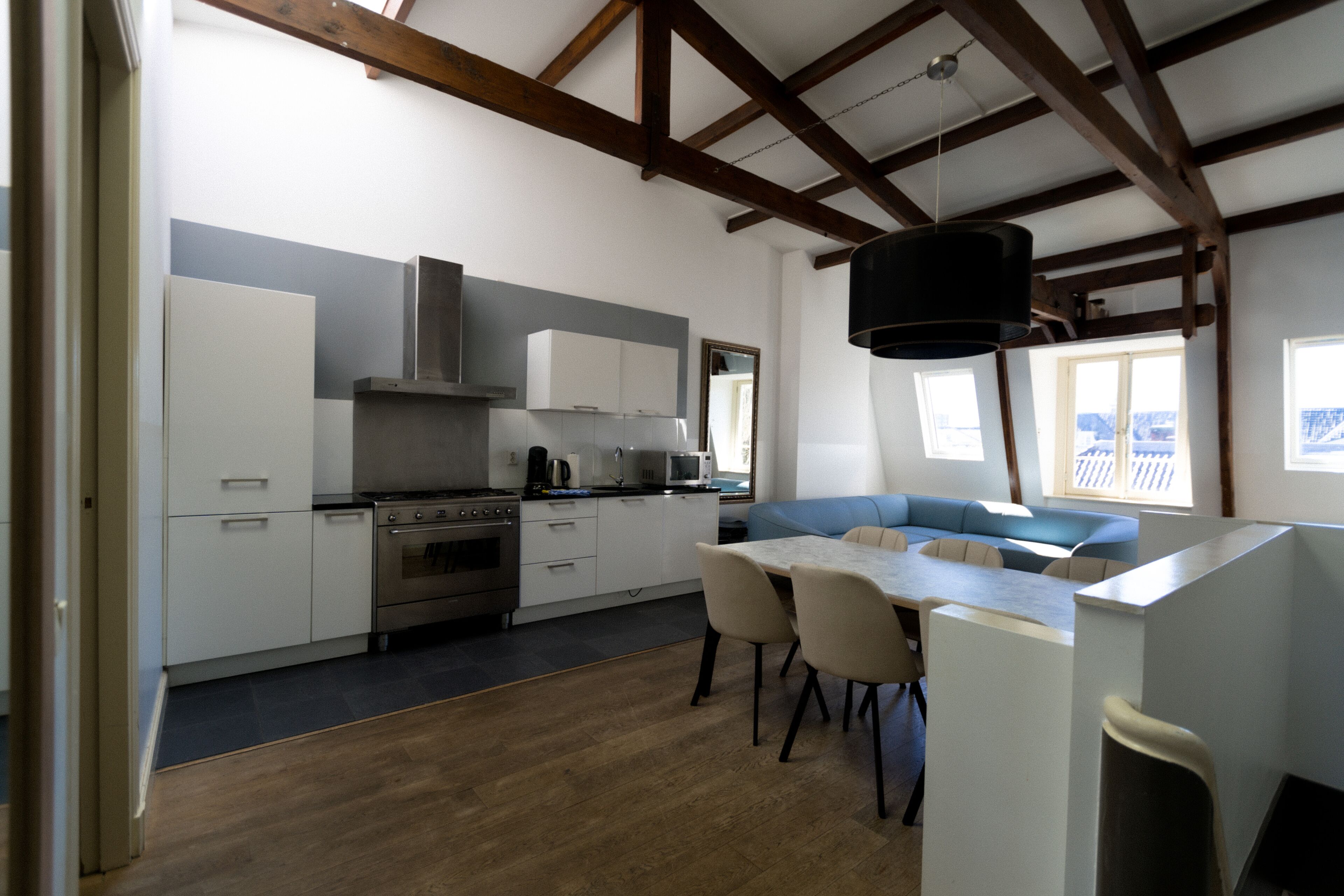A modern kitchen with white cabinets, a built-in oven, and a dining area with a table and chairs.