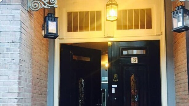 A building entrance with a black door marked '35', a light fixture above, and a brick wall. - Plantage Hortus Apartments (Amsterdam)