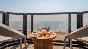 Een tafel met ontbijt spullen en uitzicht op het strand.