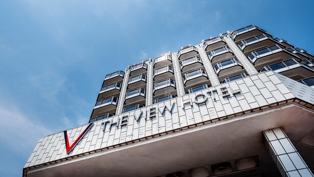 Een meerhoog hotel met een opvallend bord waarop 'The View Hotel' staat.