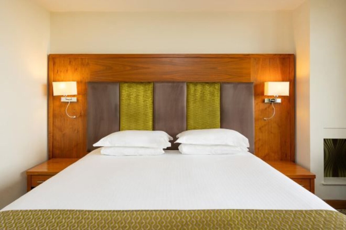 A double bed with a wooden headboard, two bedside lamps, and a patterned bedspread.