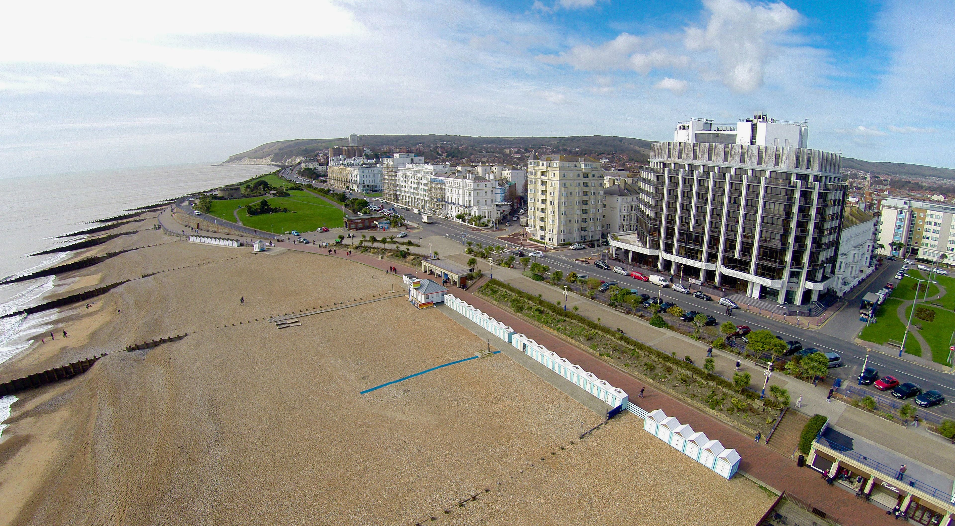 Un paysage urbain côtier avec une plage, des bâtiments modernes et un ciel dégagé.