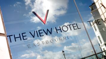 Una ventana de vidrio con el texto "The View Hotel Eastbourne" y una marca de verificación roja.