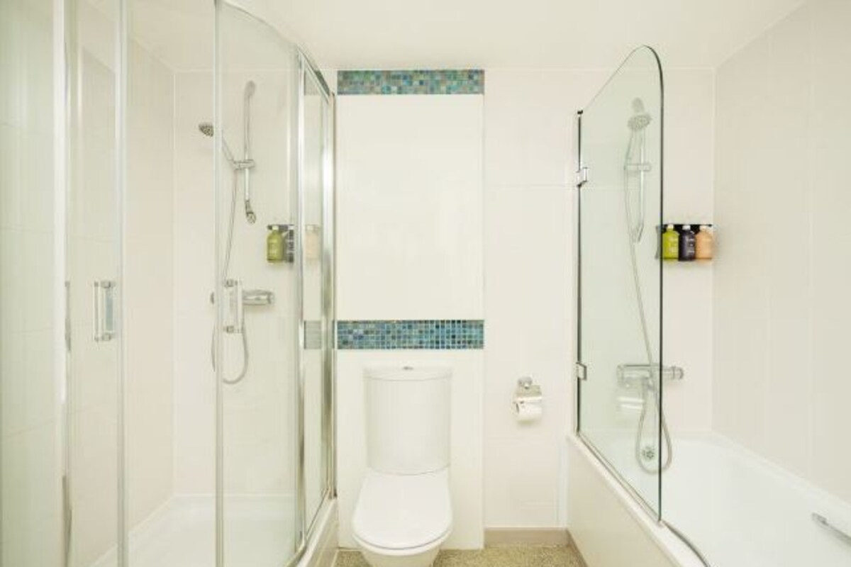 A bathroom with a glass-enclosed shower, a toilet, and a bathtub.