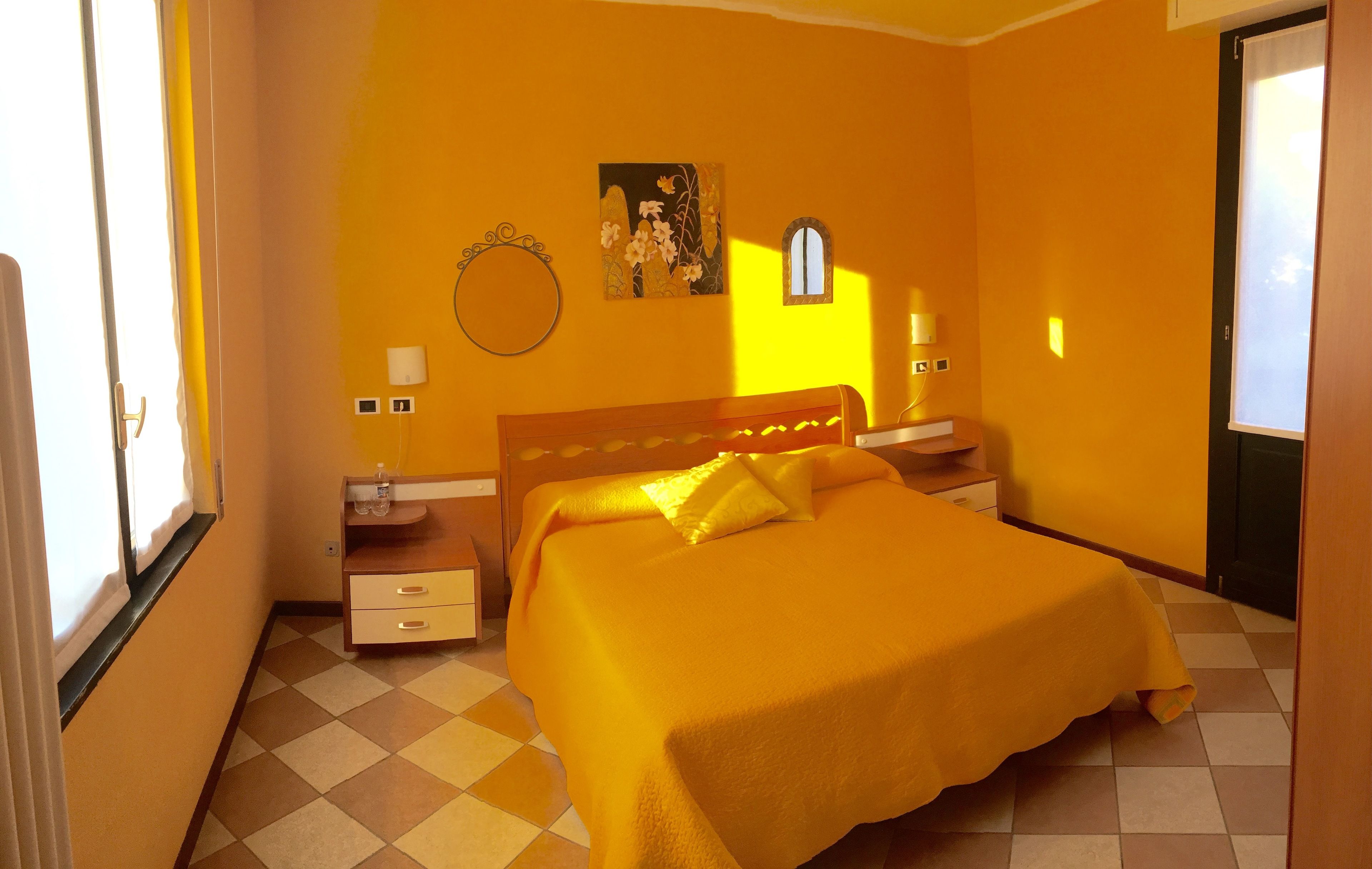 Una camera da letto con un letto, un comodino, una cassettiera, una finestra e una porta.