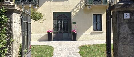 A stone pathway leading to a building with green shutters and a number '2' sign.