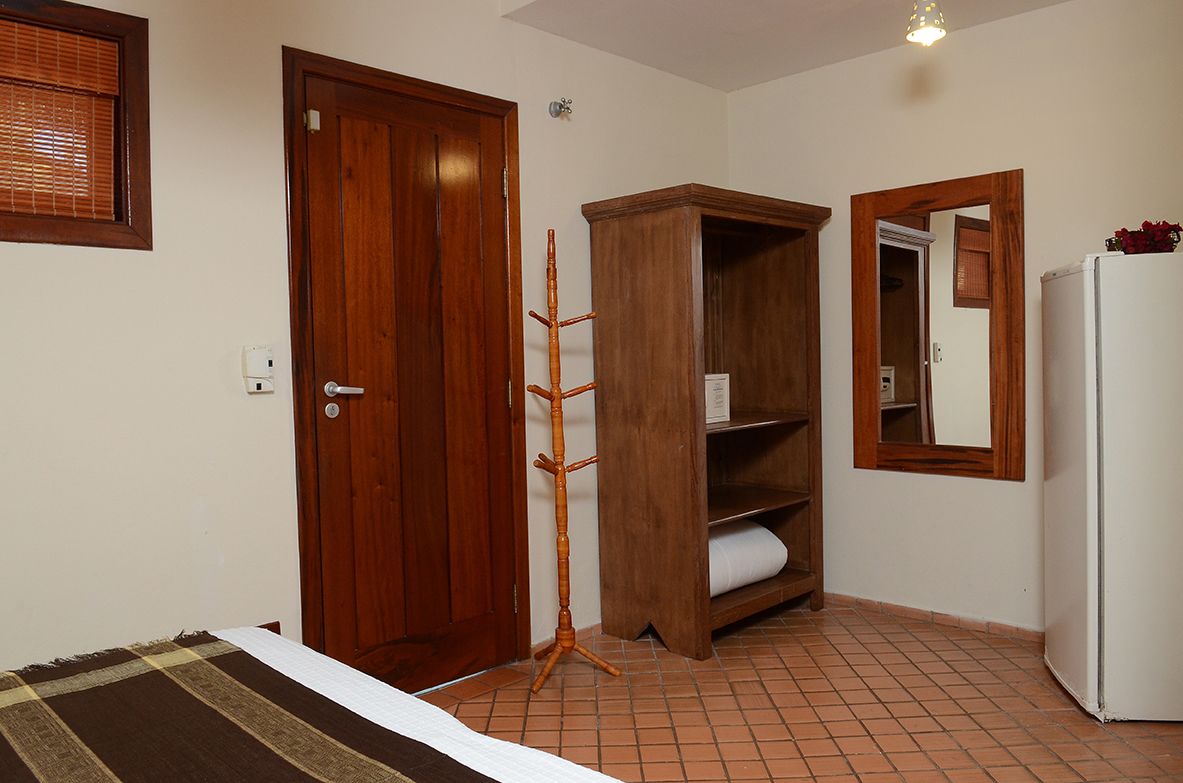 Un dormitorio con cama, armario de madera y refrigerador blanco.