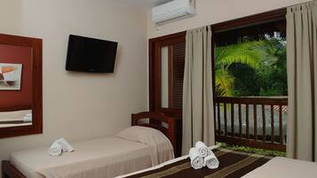 Une chambre d’hôtel avec deux lits, une télévision, la climatisation et une vue sur un jardin tropical.