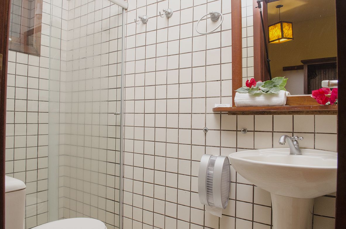 A bathroom with white tiled walls, a white sink, and a mirror above it.