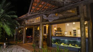 A restaurant with an outdoor seating area, a tiled backsplash, and a wooden pergola.