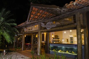 Un restaurante con área de mesas al aire libre, salpicadero de azulejos y una pérgola de madera.